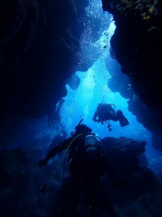 オリンパスTGシリーズの水中ワイドモードで撮った水中洞窟をダイバーが泳いでいる様子